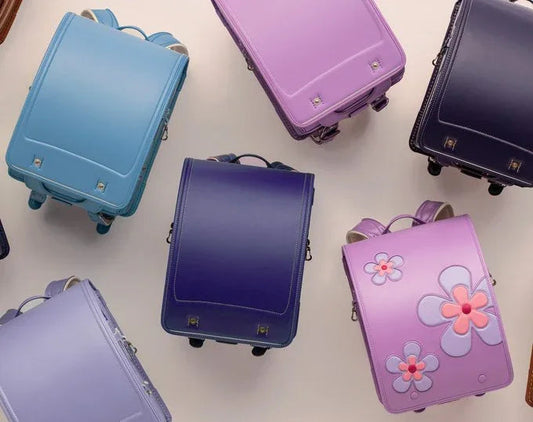 Colorful Japanese randoseru backpacks for kids in pastel blue, purple, and pink with floral designs