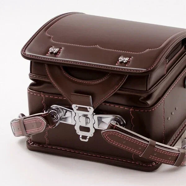 Close-up of a brown Japanese randoseru backpack with pink stitching and metal clasp