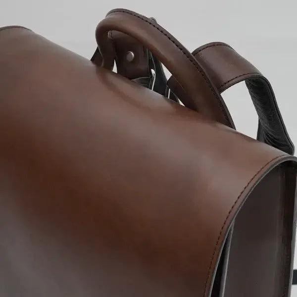 Brown Japanese randoseru leather schoolbag with curved handle, close-up view