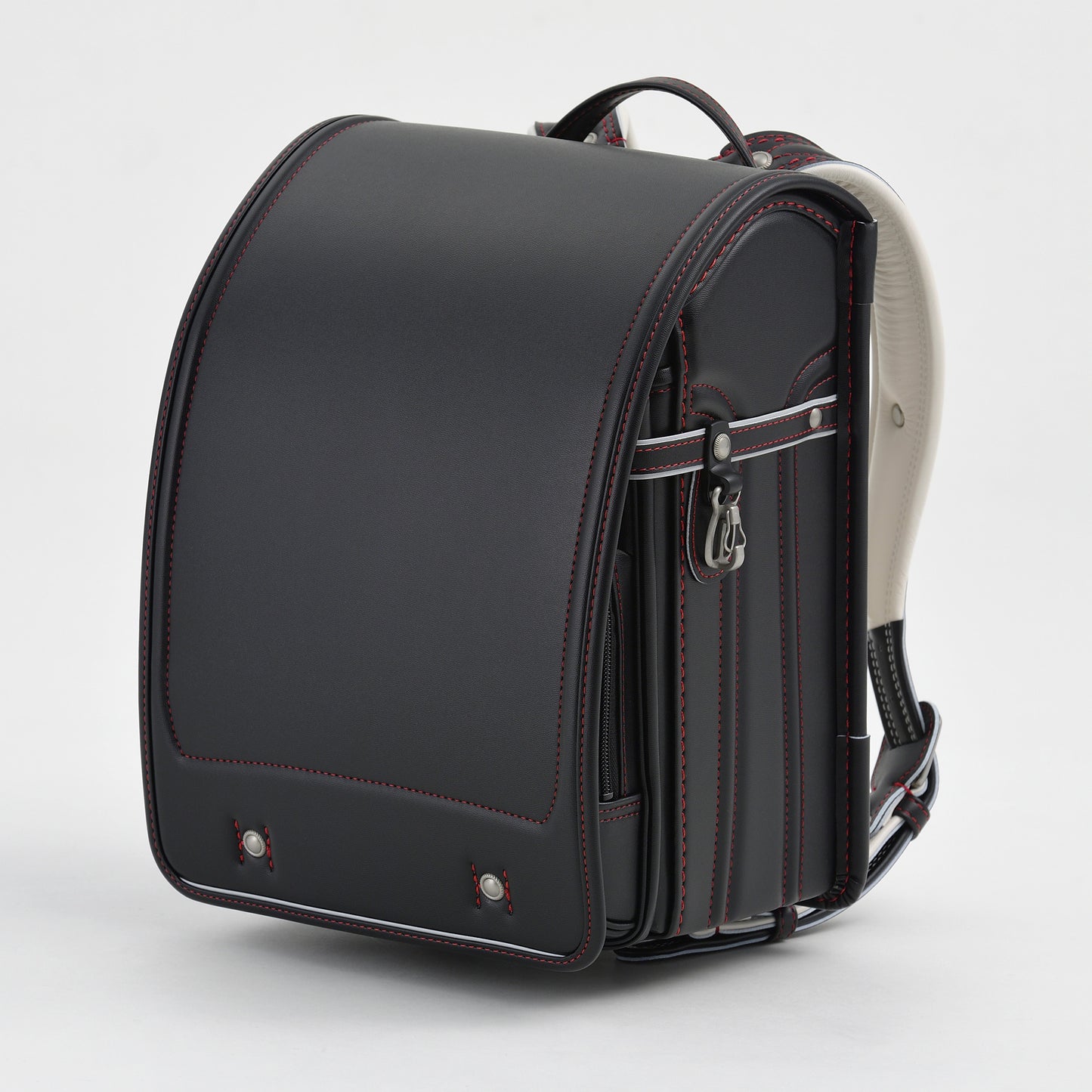 Japanese randoseru black leather backpack with red stitching on white background