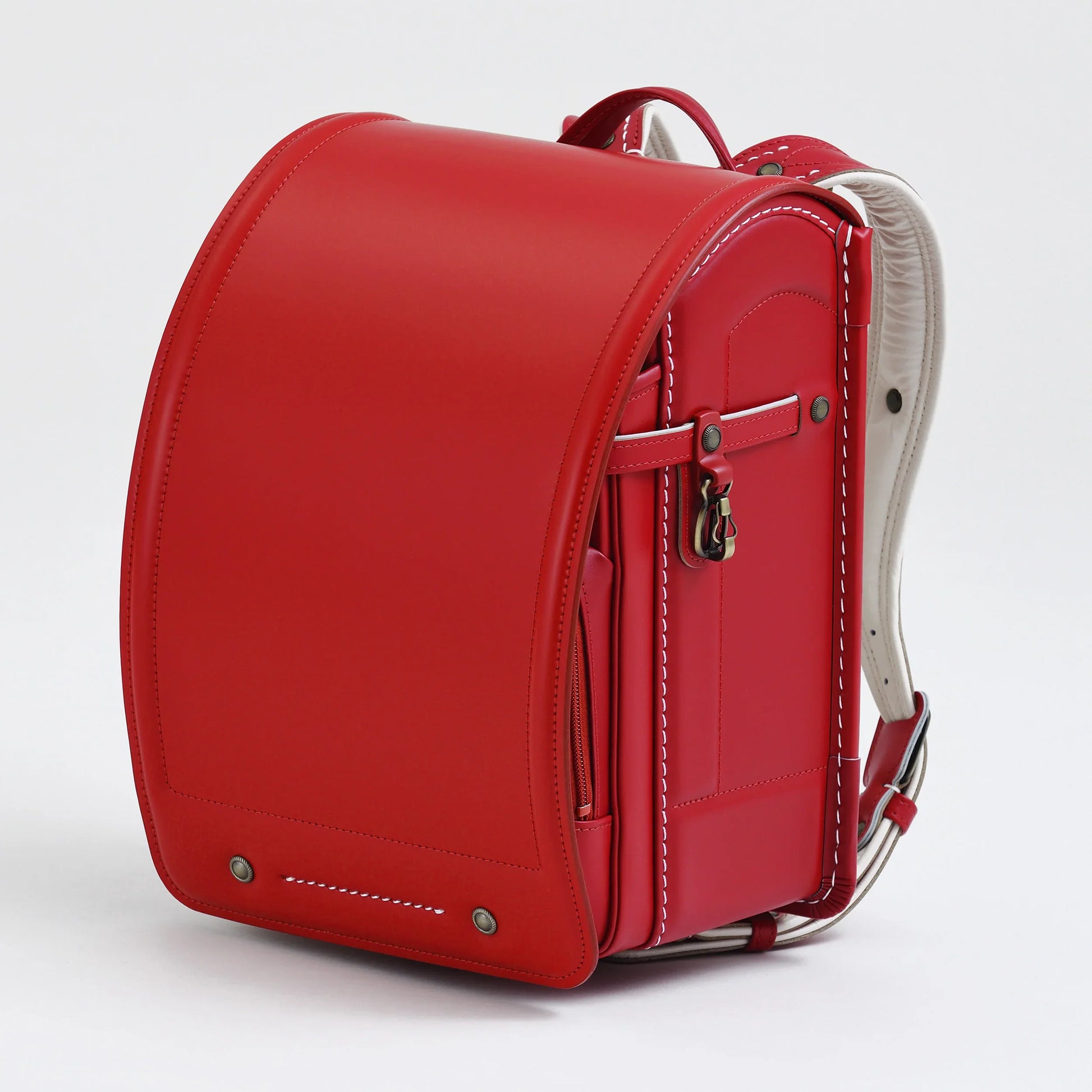 Red Japanese randoseru backpack with white stitching on a plain background