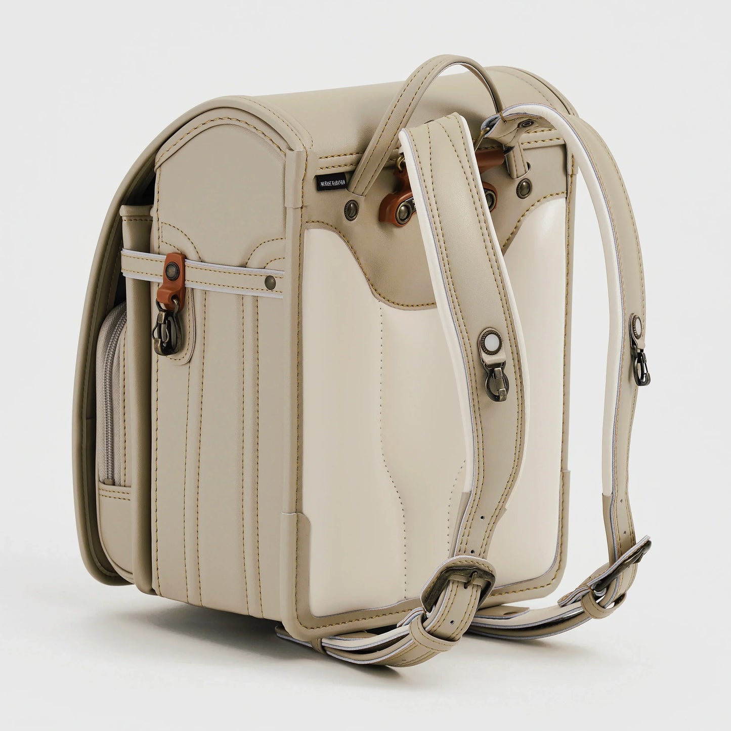 Beige Japanese Randoseru backpack with adjustable straps and side pocket on white background