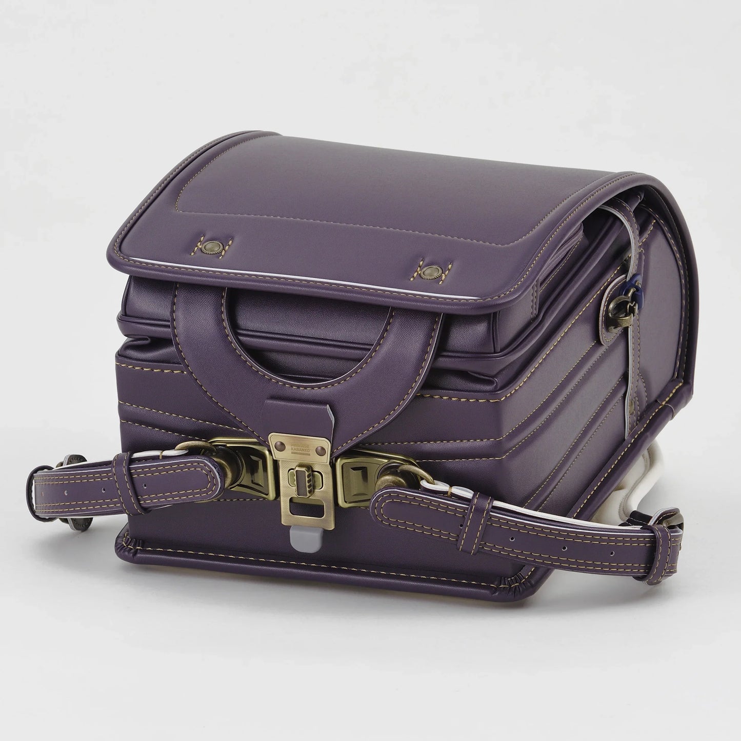 Purple Japanese randoseru backpack with brass buckle and detailed stitching on white background