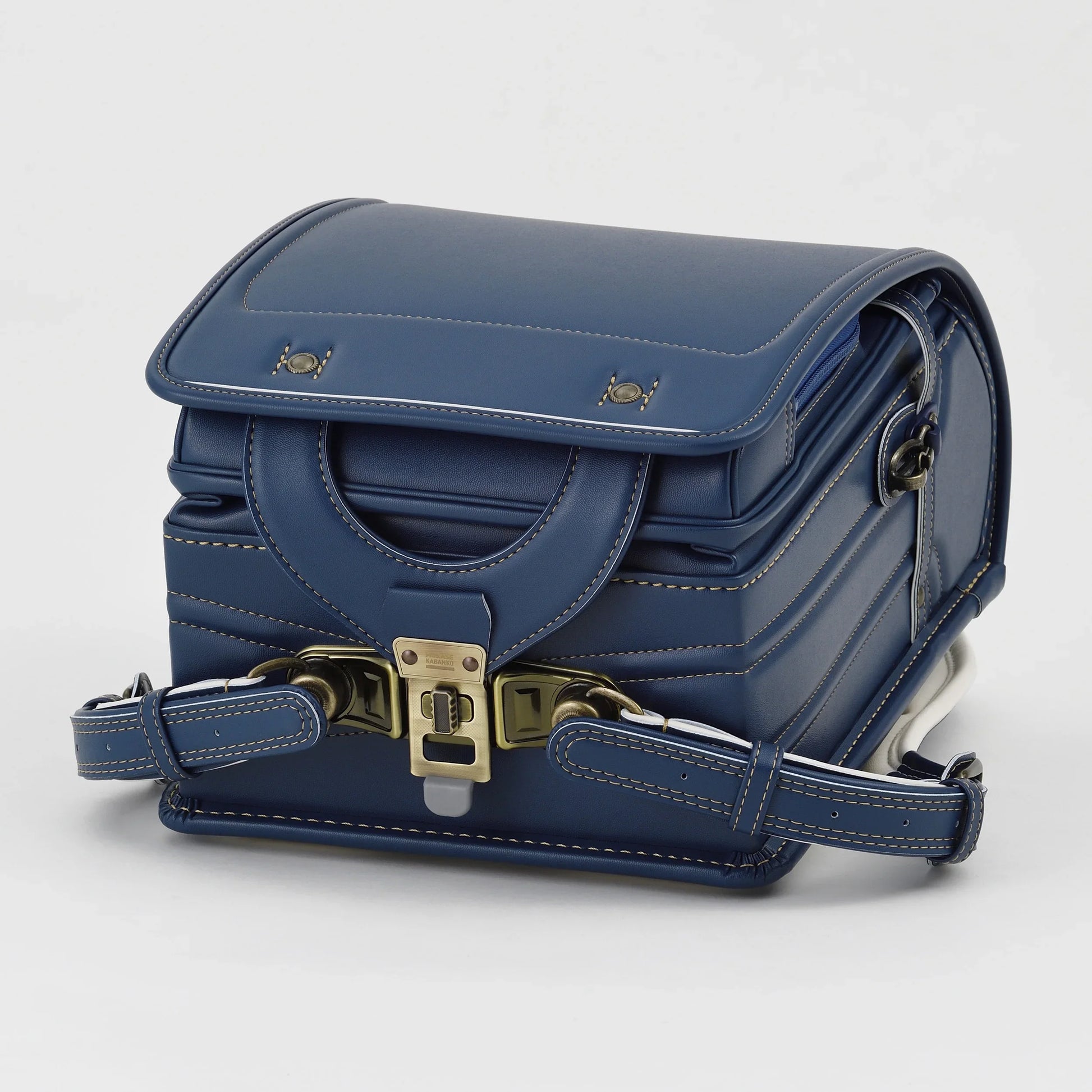 Navy blue Japanese randoseru backpack with white stitching and metal clasp on white background
