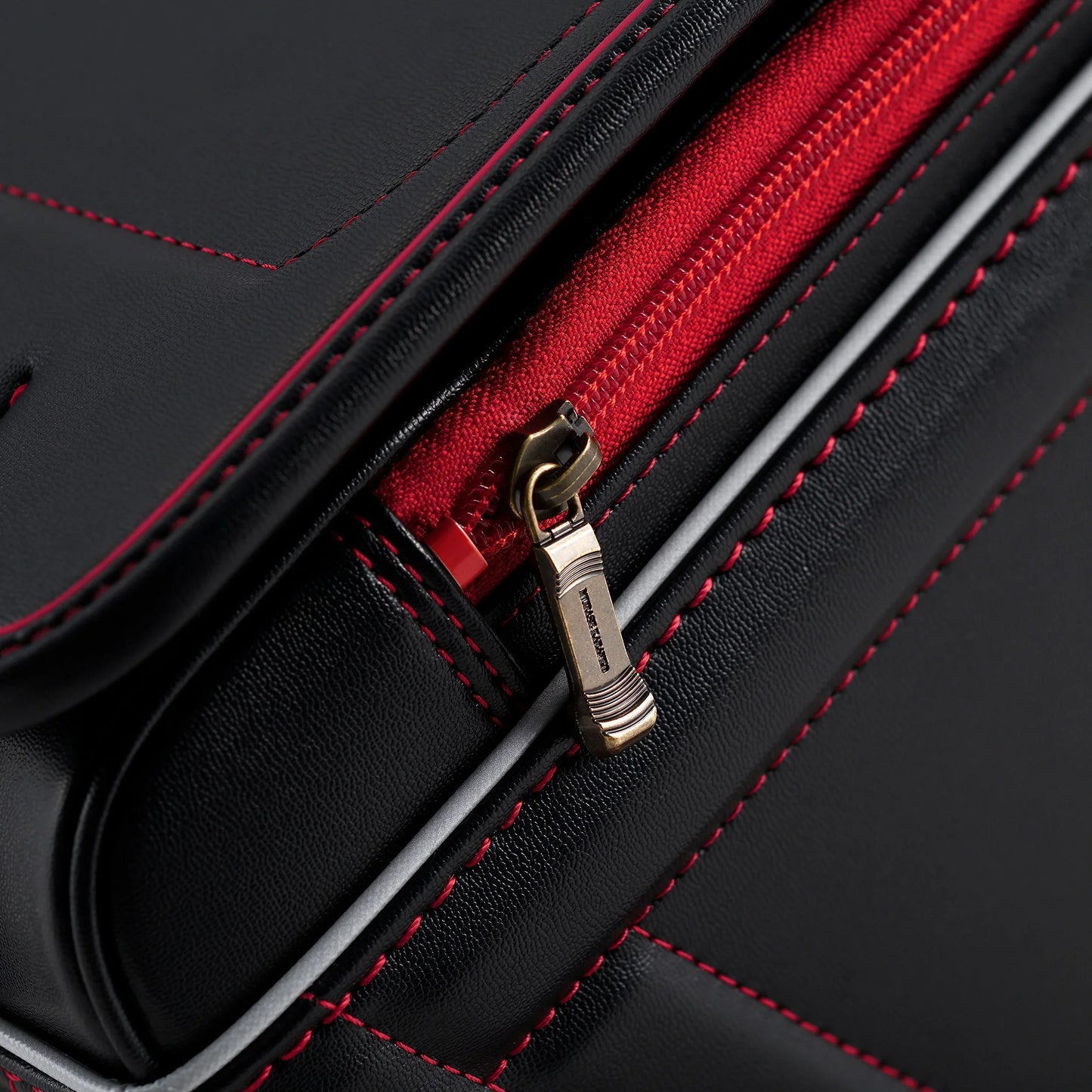 Close-up of Japanese randoseru backpack in black leather with red stitching and zipper.