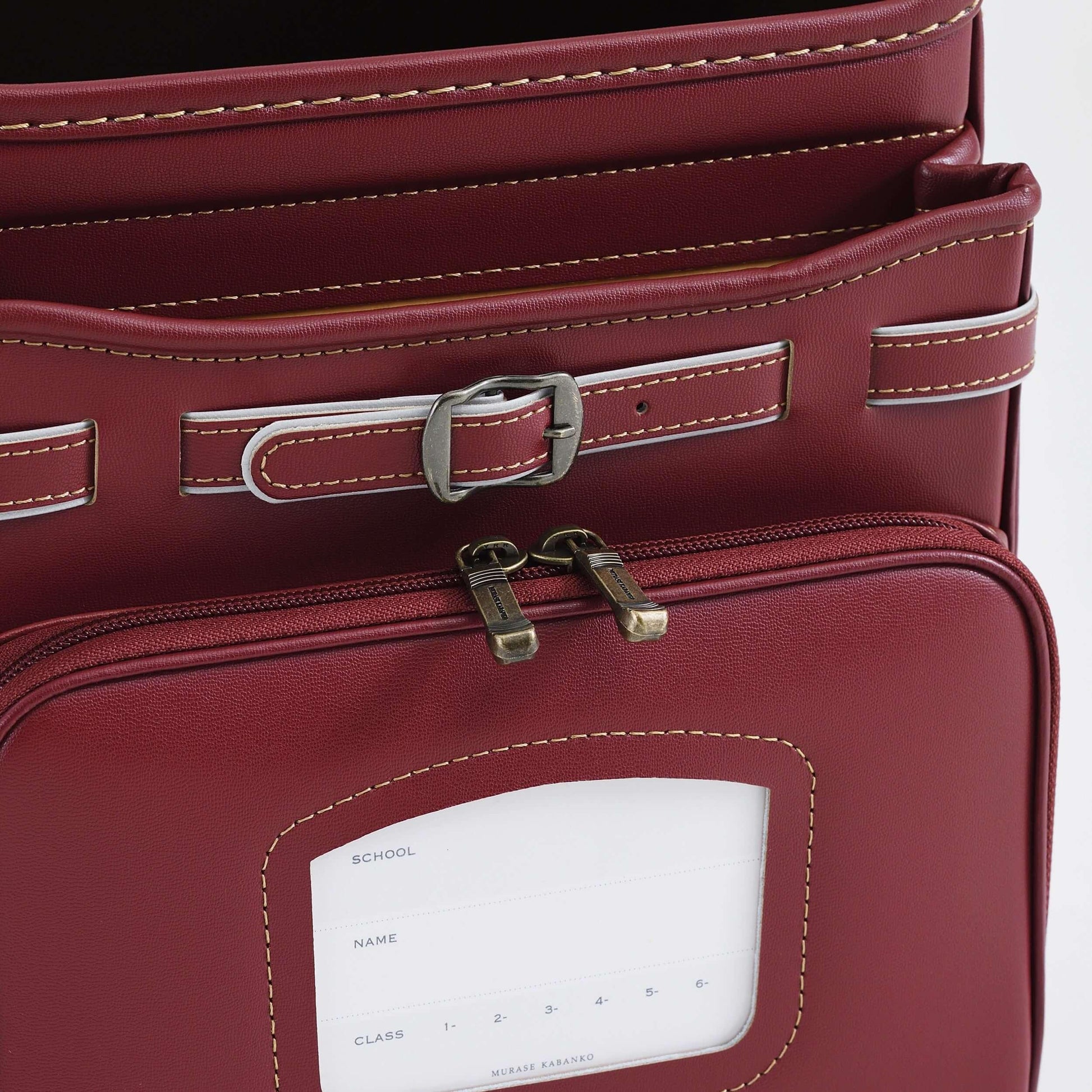 Randoseru Bolca Leather red backpack by Murase Kabanko with metal buckle, white stitching, and front name-tag window.